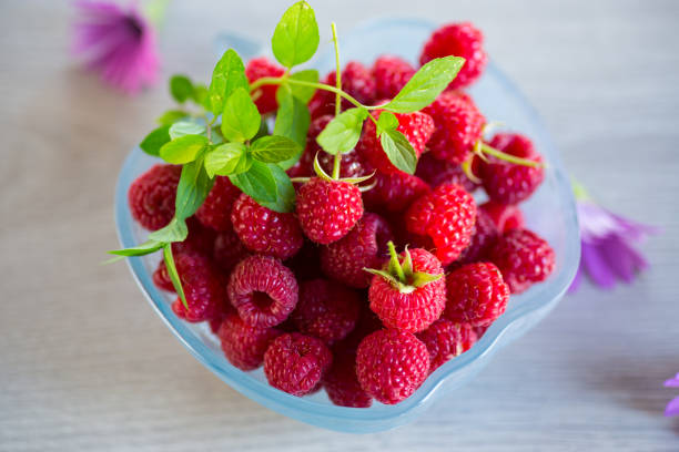 istock Fresh ripe raspberries in a glass bowl on wooden table. 1746645367