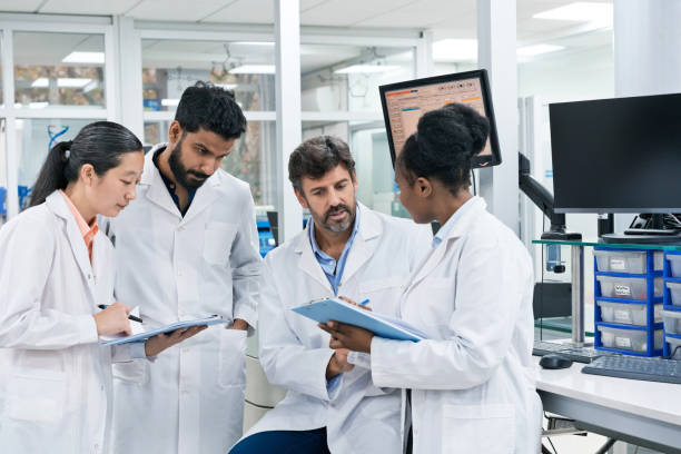 istock Team of pharmacists discussing over while writing on clipboards at laboratory 1746648077