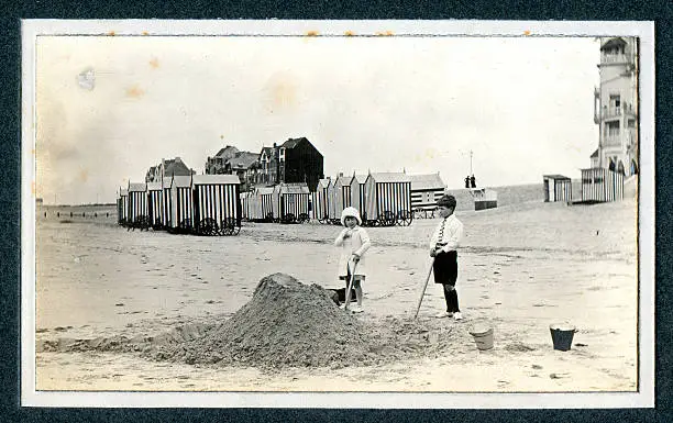 Vintage photograph of two Edwardian children playing in the sand at the seaside. Knokke, Belgium.