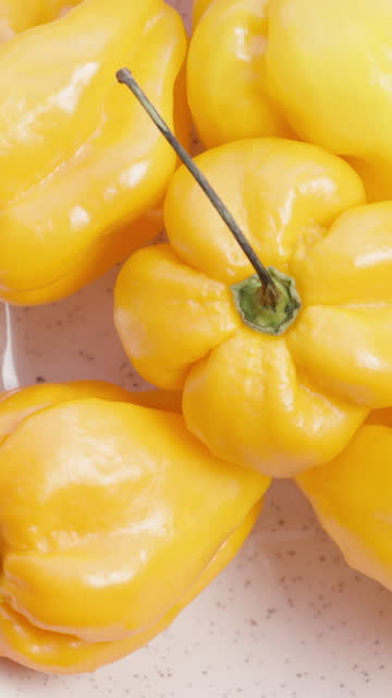 Vertical video. I place a plate of Yellow Habanero peppers on a white background, viewed from above. Slider