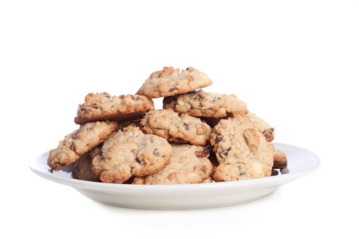 Plate full of chocolate chip cookies with walnuts on white background.