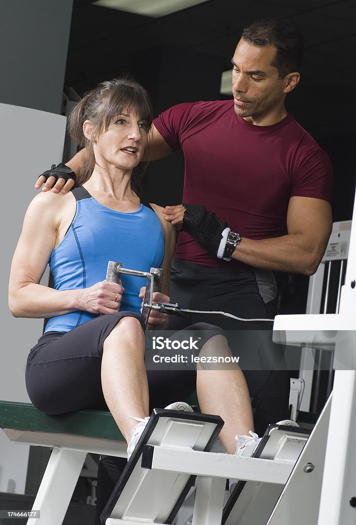 Health Club Workout on Rowing Machine "Woman working with her personal trainer on the rowing  machine at the gym.Click below for a lightbox of more in this series, plus my other fitness images:" Active Lifestyle Stock Photo