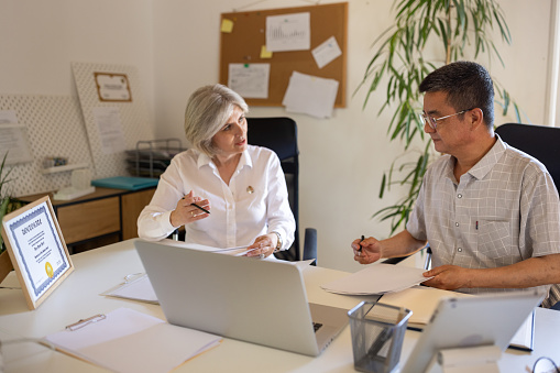 Mature man and woman working together in modern office.
