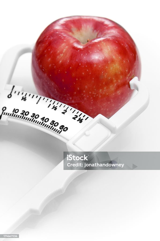 Caliper A skin fold/body fat caliper pinching an apple. Concept of healthy eating. Body Mass Index Stock Photo