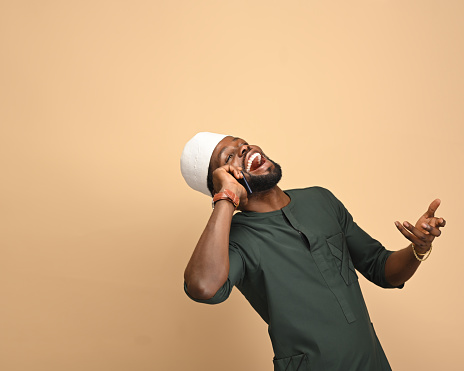 A beautiful energetic African American man is happy and excited expressing a winning gesture as he announces good news on a mobile call. Successful and celebrating victory, triumphant, on red background finance winning concept