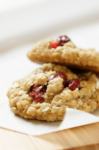 Healthy oatmeal cookies with plump cranberries on bakery parchment paper.  Very shallow DOF.