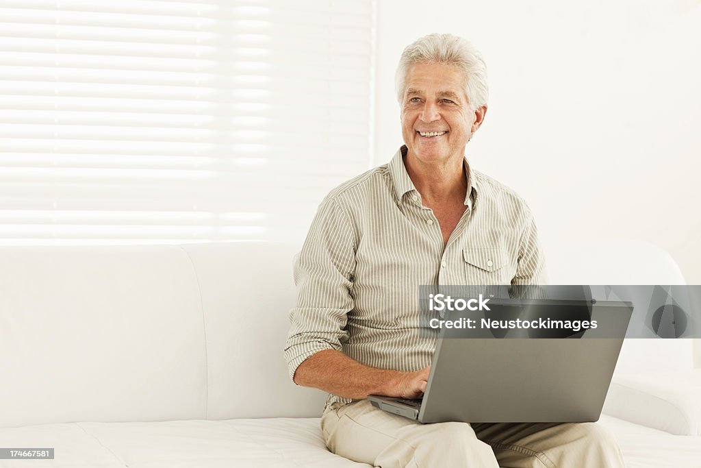 Sonriente hombre senior utilizando portátil en casa - Foto de stock de 60-64 años libre de derechos