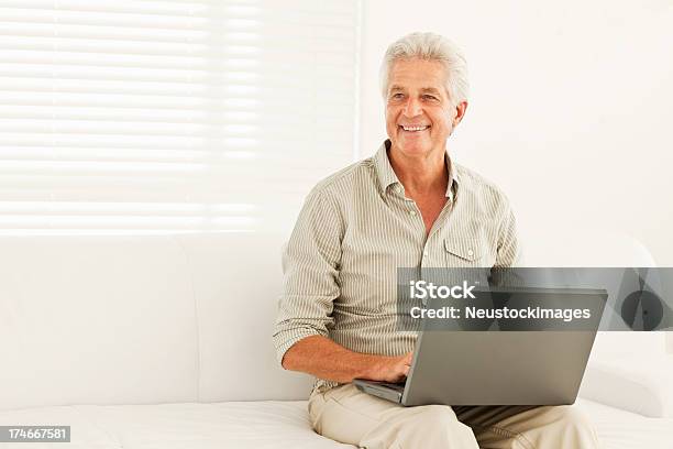 Sonriente Hombre Senior Utilizando Portátil En Casa Foto de stock y más banco de imágenes de 60-64 años