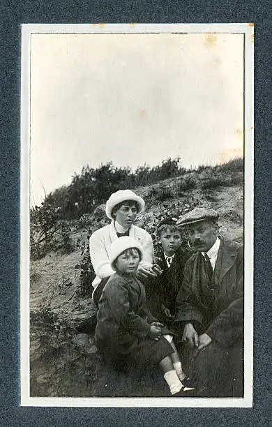Vintage photograph of an Edwardian family on a day out at the seaside sitting in the sand dunes. Knokke, Belgium.