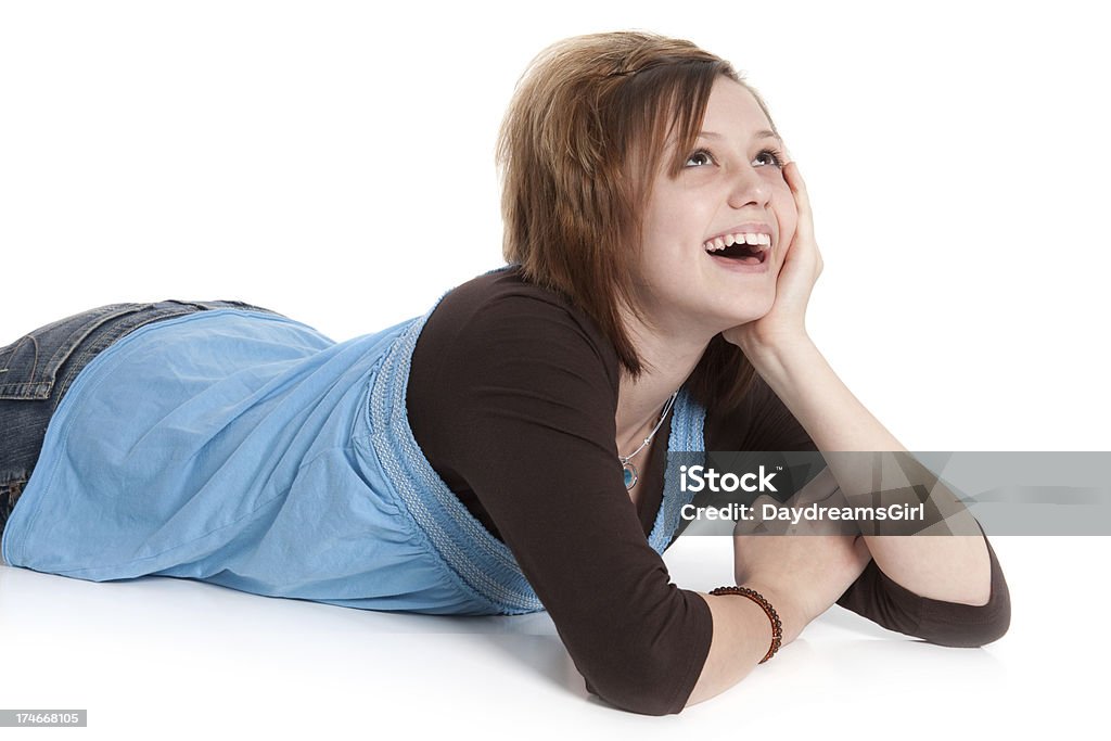 Teenage Girl Laughing Looking Up Lying on White Background "Casual teenage girl lying on white floor background, looking up and laughing." Teenage Girls Stock Photo