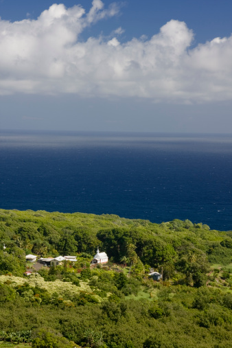 Beautiful little white chapel surrounded by lush tropical vegetation with the deep blue ocean in the distance