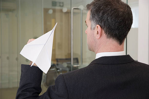Businessman aiming a paper aeroplane stock photo