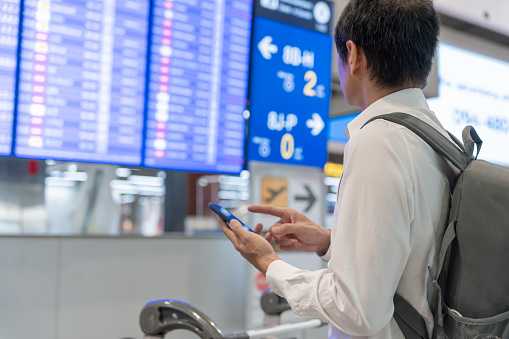 Business man using mobile phone to book plane ticket through online application, sitting on travel checking travel time on board at airport, travel, payment, due, booking, online, check in