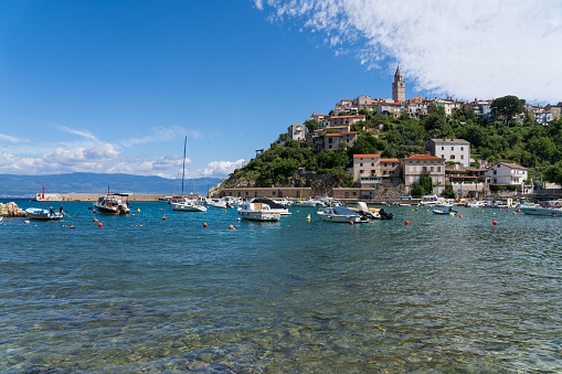 sunny summer day in little harbour in the adriatic sea, with old historical town on hill