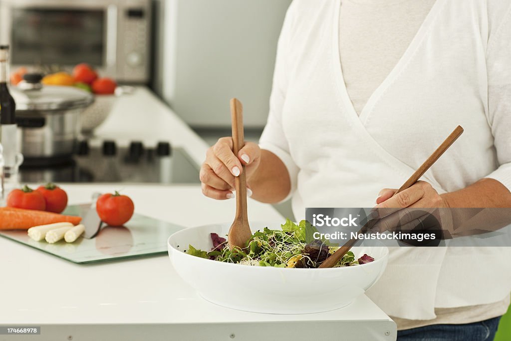 Kobieta z Łyżeczką wymieszać surowe warzywa w misce - Zbiór zdjęć royalty-free (Cięcie w linii środkowej)