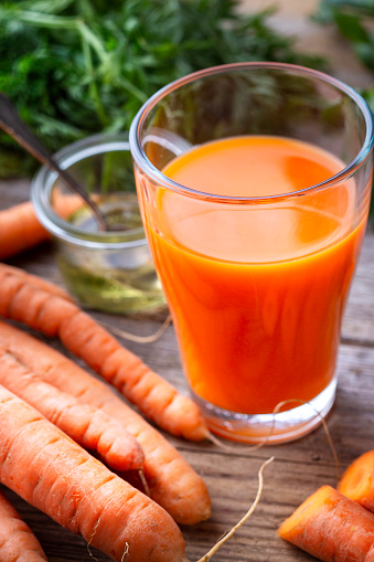 juice in a glass container surrounded by fresh vegetables and fruits on white boards