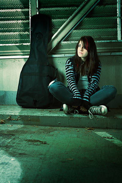 Street Musician and Guitar Vt Subject: A young street musician sitting on the curb of the street. black hair emo girl stock pictures, royalty-free photos & images