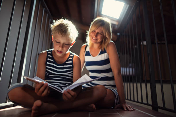 Little boy is doing his homework - he is practicing reading aloud. Mother is helping the son.\nShot with Nikon D810.