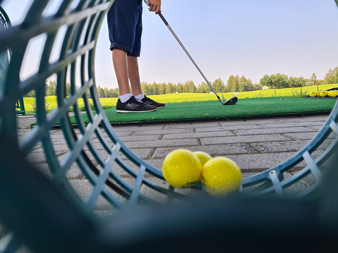 Golfer child on practice mat during golf lesson. Holding golf club