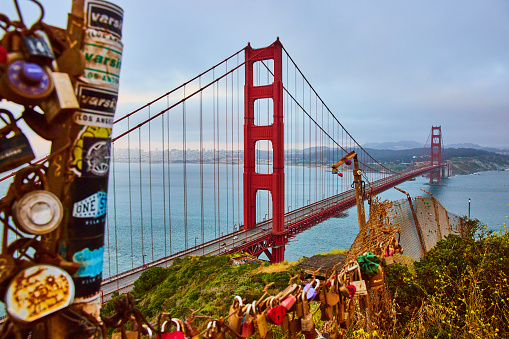 Image of Golden Gate Bridge at sunset with fence covered in padlocks on overlook