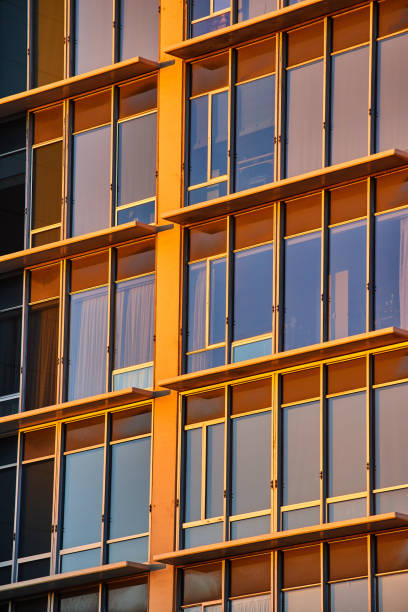 istock Golden light on tall office windows of skyscraper with ledges 1746713108