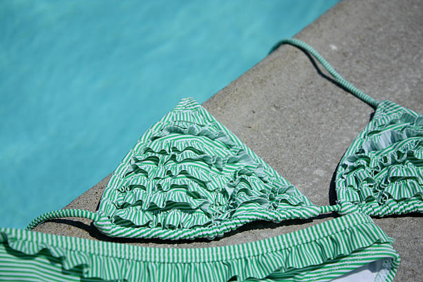 Bikini bikini top and bottoms rest on a pool deck ruffled bikinis stock pictures, royalty-free photos & images