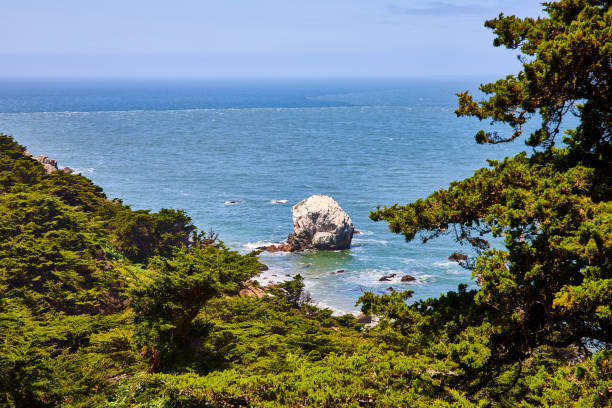 istock Greenery framing giant white rock sticking out of shallow bay waters with distant deeper blue water 1746717113