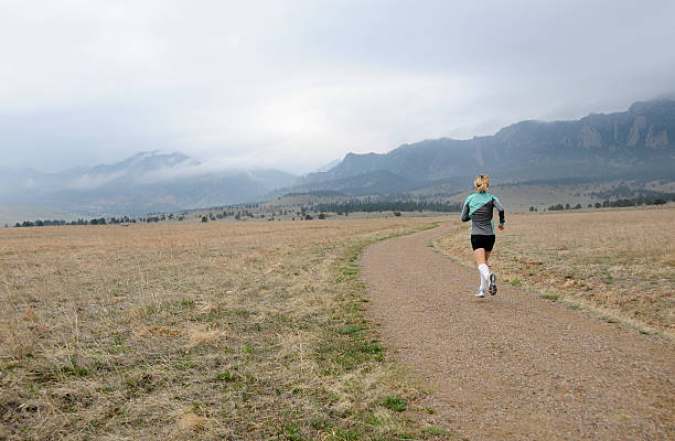 Woman running on mountain trail stock photo