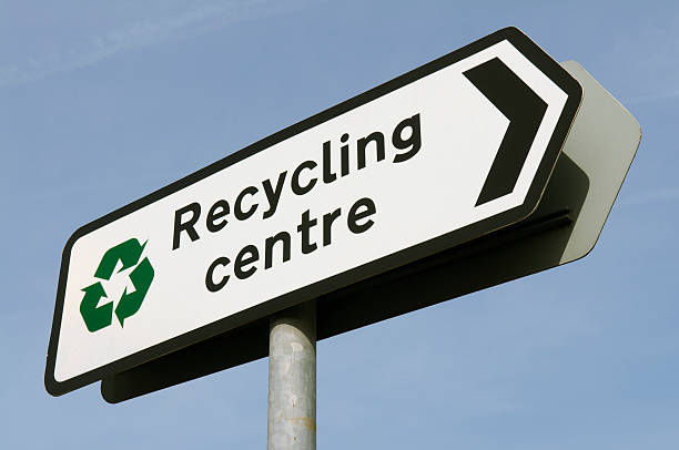 Recycling Centre Sign Clear Blue Sky Sign for recycling center points into blue sky recycling center stock pictures, royalty-free photos & images