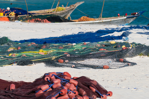 red fishing net on sandy beach, background other fishing nets and fishing boat, Zanzibar ,Tanzania.