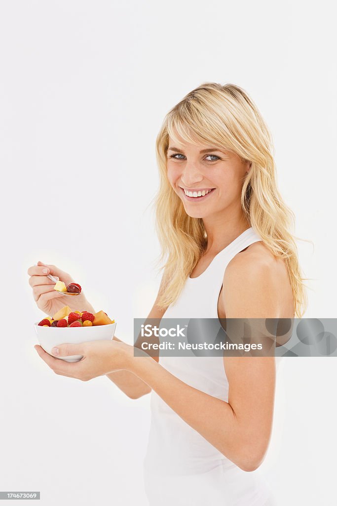 Souriante jeune femme tenant une salade de fruits - Photo de 20-24 ans libre de droits