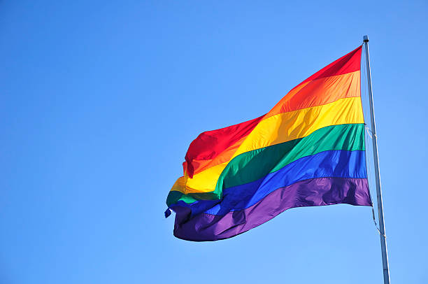 Rainbow flag Rainbow flag over blue sky. pride flag stock pictures, royalty-free photos & images