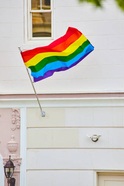 istock Rainbow pride flag stretched out in the wind against white building with white garage 1746735005