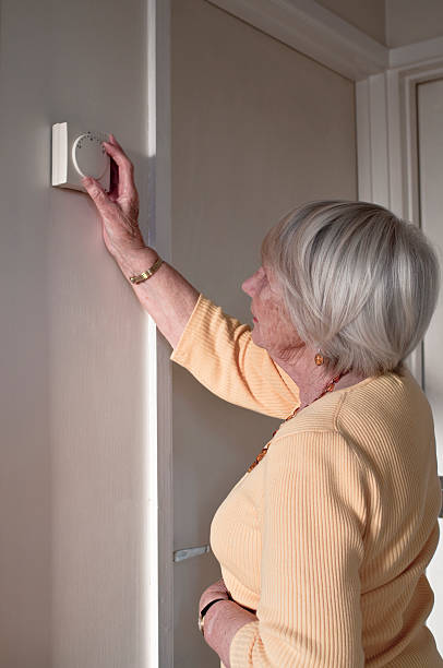 istock Elderly Lady Adjusting The Central Heating Thermostat 174673962