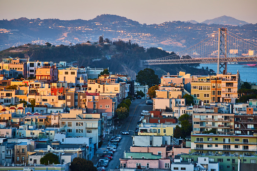 Image of San Francisco with golden sunset light fading off buildings and Oakland Bay Bridge