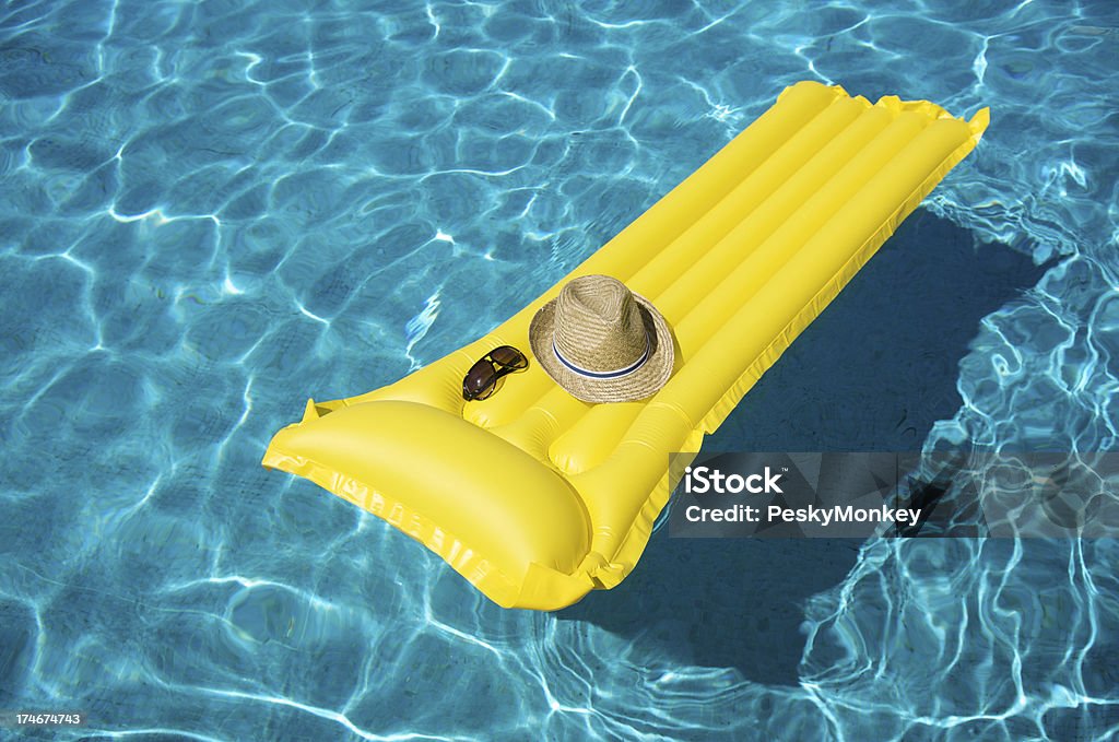 Yellow Pool Raft Floats with Hat and Sunglasses Yellow pool raft floats on rippling blue water with a man's hat and sunglasses Floating On Water Stock Photo