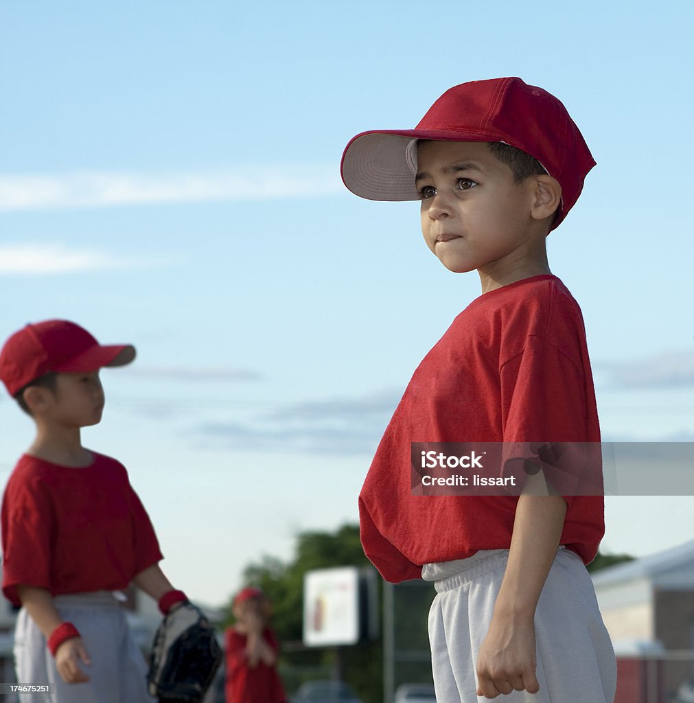 Boys Play Baseball "3 boys stand in the outfield playing ball. They wear red t-shirts and caps for their sports uniform. One Latino, one Asian and one Caucasian." Baseball - Sport Stock Photo