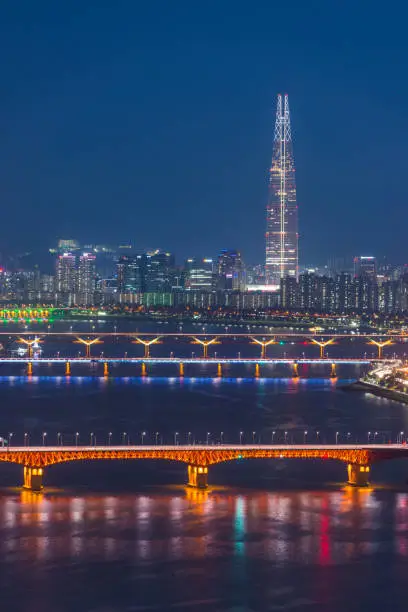 The glittering neon night skyscrapers of downtown Seoul along the colourfully illuminated highways and bridges of the Han River in South Korea’s vibrant capital city.
