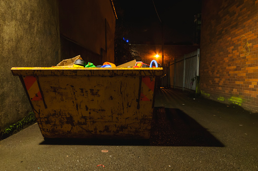 A yellow builders skip at night