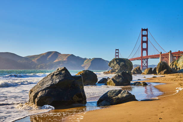 istock Sunny beach with waves crashing against boulders and distant Golden Gate Bridge 1746760322
