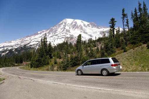 A minivan drives by on a curving road near Mt. Rainier in Washington State.