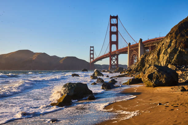 istock Waves rolling into sandy beach with massive boulders and Golden Gate Bridge near sunset 1746770185