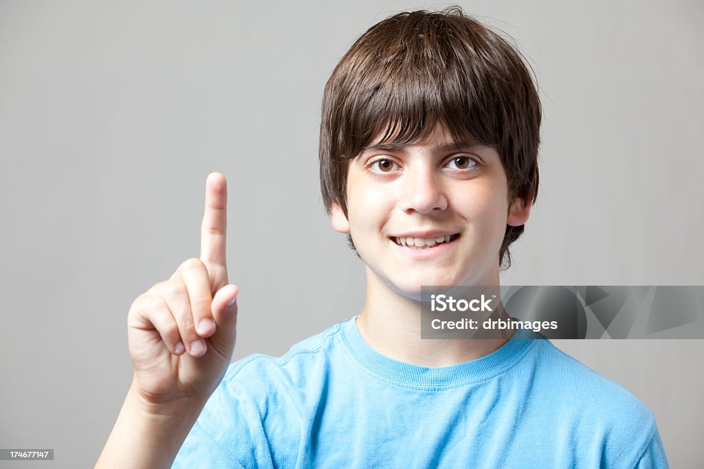 Boy Holds Up One Finger A young boy smiles and holds up one finger. Isolated on gray.http://s3.amazonaws.com/drbimages/m/phibob.jpg Child Stock Photo