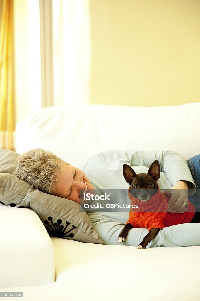 Привлекательные зрелая женщина на диване с ее собака - Стоковые фото 60-64 года роялти-фри