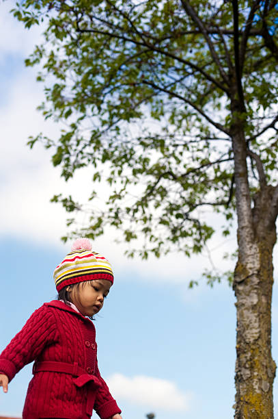 little asian girl in red sweater with blue skies stock photo