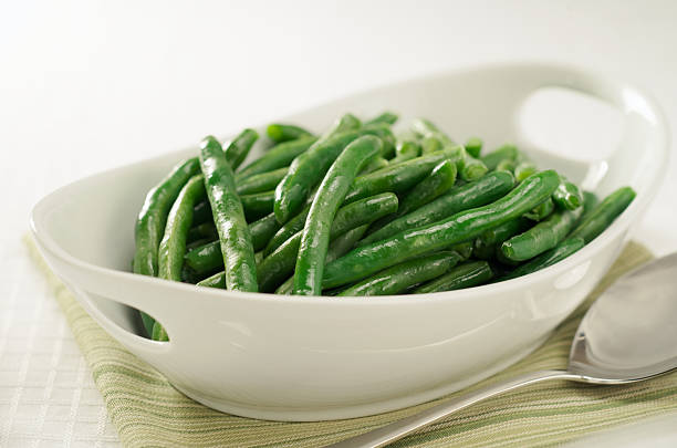 Healthy Steamed Green Beans in White Serving Bowl Freshly steamed green beans ready to be served. steamed photos stock pictures, royalty-free photos & images