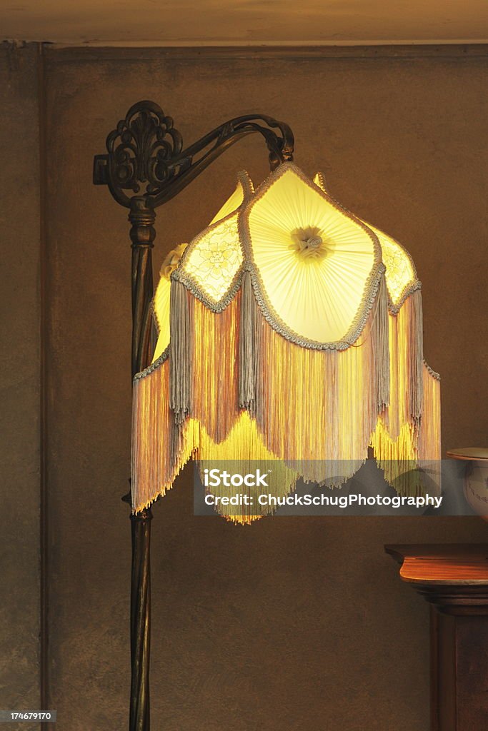 Lamp Lampshade Fringe Home Decor Antique floor lamp with illuminated fringed lampshade in luxury home creating moody composition. Floor Lamp Stock Photo