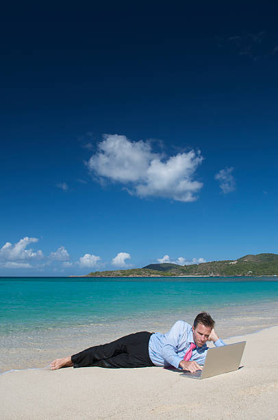 istock Businessman Lies Using Laptop on Tropical Beach 174679181