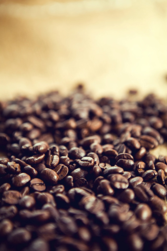 Fresh aromatic coffee beans on display; shallow depth of field with plenty of room for your text or images.  Vertical with copy space.