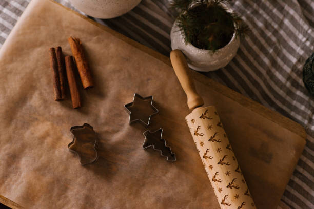 istock Ginger cookie molds, rolling pin and cinnamon sticks on a sheet of parchment on the table 1746800029